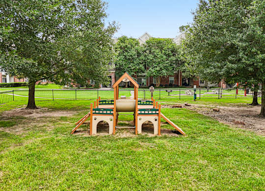 A playground with a slide and a sandbox in the foreground.