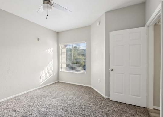 A room with a ceiling fan and a door. at Sweetwater At Metro North Apartments, Arizona 85029