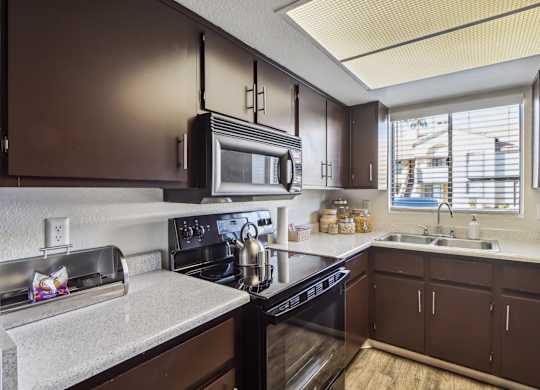 A kitchen with brown cabinets and a black stove top oven.