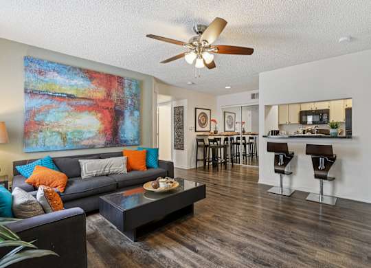 A living room with a grey couch and a painting on the wall.