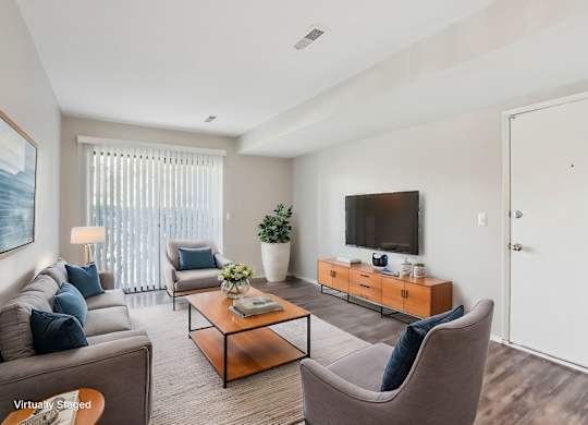 A living room with a brown sofa, a grey armchair, a glass coffee table, a television, and a potted plant. at Millennium at Creve Coeur, Missouri, 63141