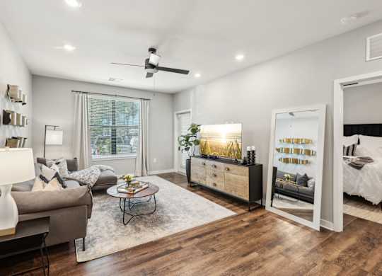 A well-lit, modern living room with a grey couch, a coffee table, and a large mirror.