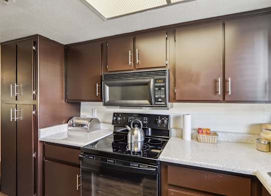 A kitchen with brown cabinets and a black stove top oven.