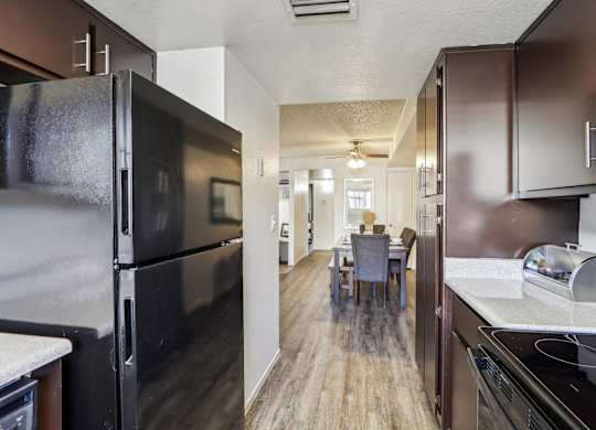 A kitchen with a black refrigerator and brown cabinets.