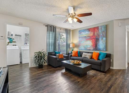 A living room with a grey couch and a painting on the wall.