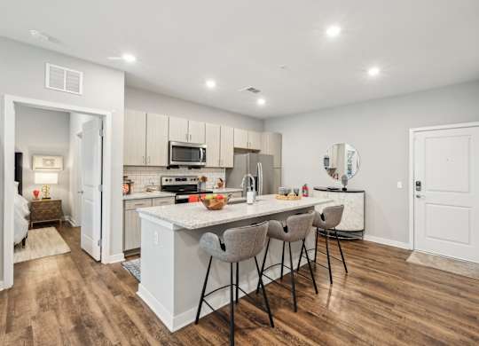 A kitchen with a white island and chairs.