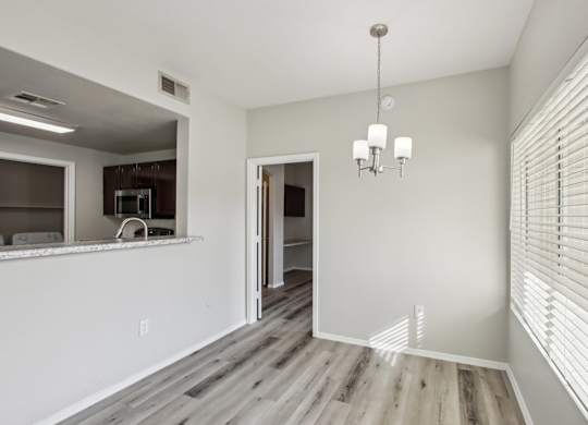 A room with a chandelier and a kitchen area in the background at Sweetwater At Metro North Apartments, Phoenix, AZ