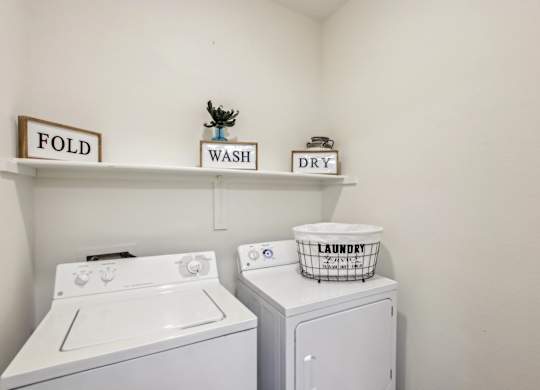 A laundry room with a washer and dryer and a laundry basket on top of the dryer at Sweetwater At Metro North Apartments, Phoenix, Arizona