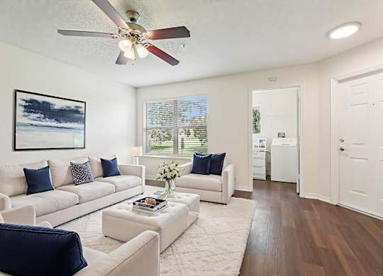 A living room with a white couch and a ceiling fan.