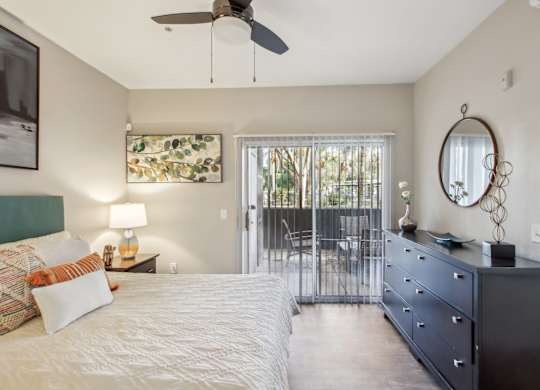 A bedroom with a bed, dresser, and a ceiling fan at Sweetwater At Metro North Apartments, Arizona 85029