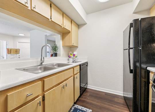 A kitchen with wooden cabinets and a black refrigerator.