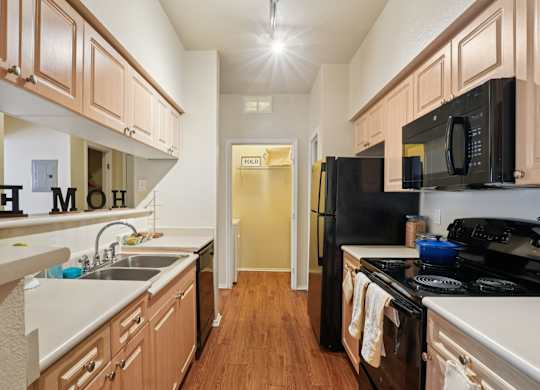 A kitchen with wooden cabinets and black appliances.