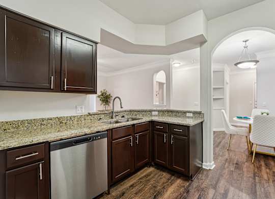 A kitchen with dark brown cabinets and granite countertops.