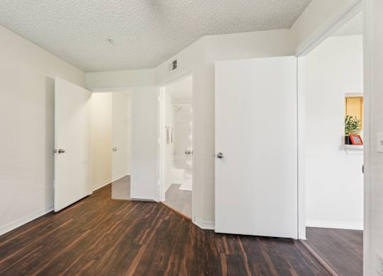 A hallway with white walls and wood floors.