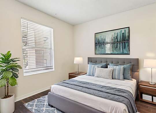 A bedroom with a large bed and a potted plant.