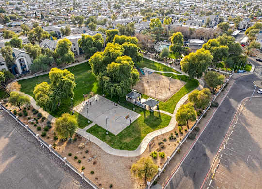 A basketball court is surrounded by trees and grass in a park at Sweetwater At Metro North Apartments, Arizona