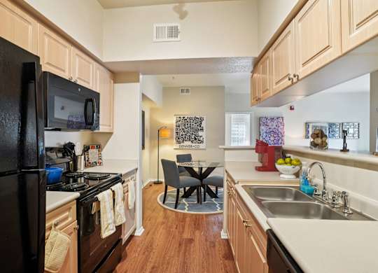 A kitchen with a black refrigerator and a sink.