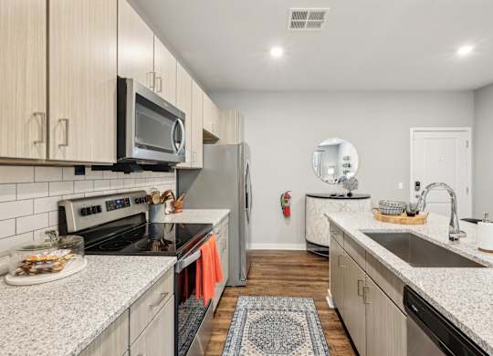 A kitchen with a refrigerator, microwave, oven, and sink.