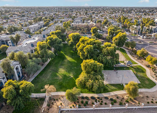 A park with a basketball court surrounded by trees and houses at Sweetwater At Metro North Apartments, Phoenix  85029