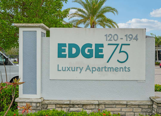 a sign for edge 75 luxury apartments in front of a palm tree at Edge75, Naples, Florida 34104