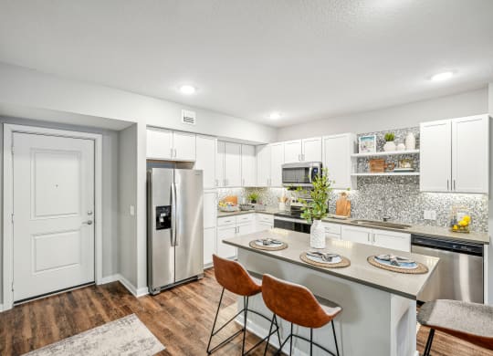 a kitchen with stainless steel appliances and a island with three chairs at Edge75, Naples, Florida 34104