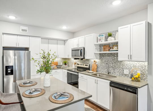 a kitchen with stainless steel appliances and white cabinets at Edge75, Naples, Florida 34104