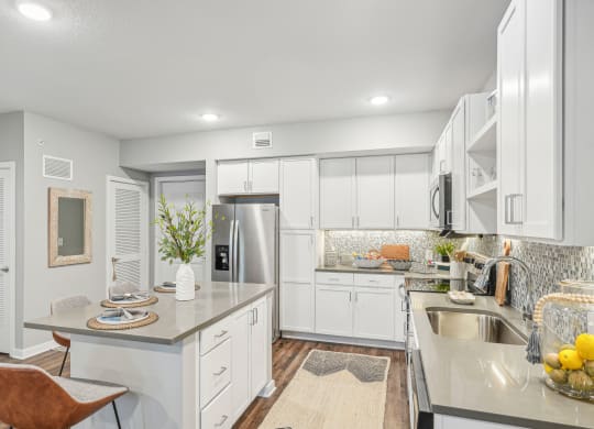 a white kitchen with stainless steel appliances and white cabinets at Edge75, Naples, Florida 34104