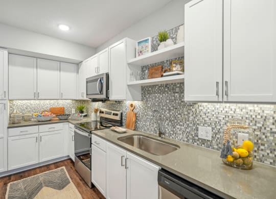 a kitchen with white cabinets and a stainless steel sink at Edge75, Naples, Florida 34104