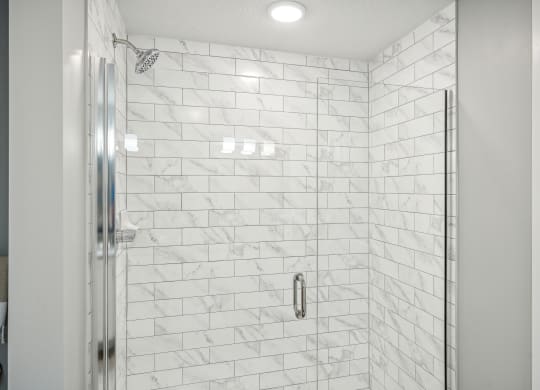 a large shower with white tile walls and a glass shower door at Edge75, Naples, Florida 34104