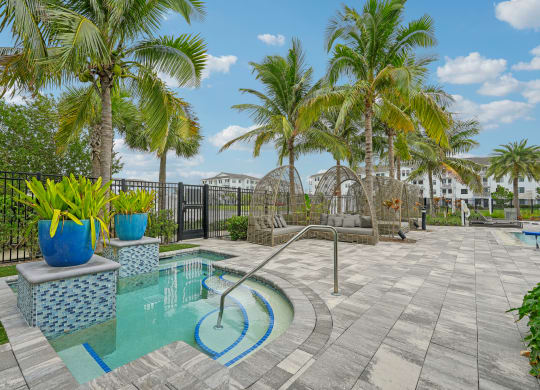 a swimming pool with palm trees and a black fence at Edge75, Naples, Florida 34104