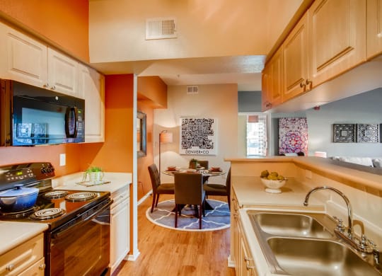 a kitchen with a sink and a stove and a dining room at Heritage at Stone Mountain, Northglenn, CO, 80233