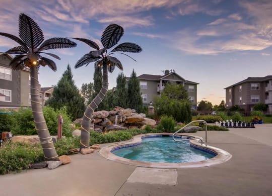 a swimming pool with palm trees in front of apartment buildings at Heritage at Stone Mountain, Northglenn, CO, 80233