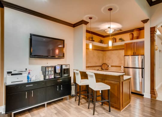 a kitchen with a bar and a refrigerator and a tv at Heritage at Stone Mountain, Northglenn, CO, 80233