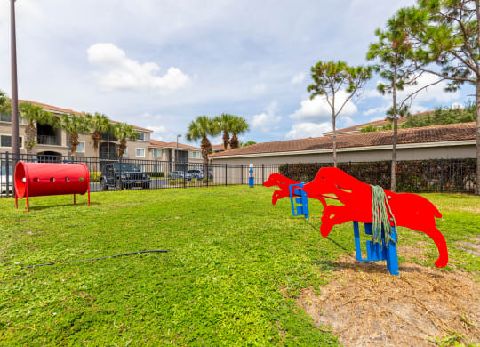 a playground with a red dog and a blue dog on a grassy field at Heritage Bay, Jensen Beach, 34957