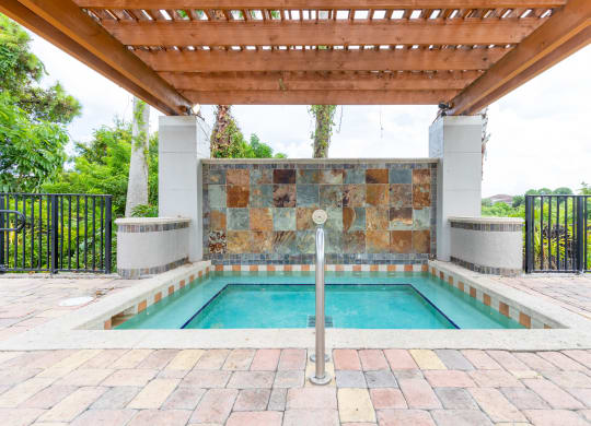 a swimming pool with a stone wall and a wooden pergola at Heritage Bay, Florida
