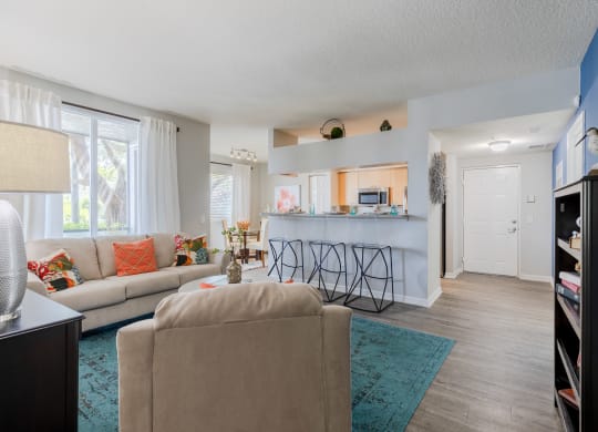 a living room with a kitchen in the background and a couch and chair in the foreground at Heritage Bay, Jensen Beach, FL 34957
