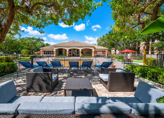 a patio with chairs and tables and a house in the background at Pembroke Pines Landings, Pembroke Pines, FL, 33025