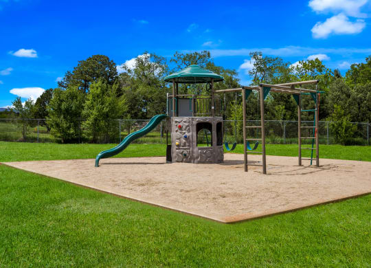 a sandpit with a jungle gym and slide in the middle of a grassy park at Broadmoor Springs, Colorado Springs, CO, 80906
