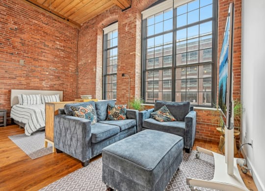 a living room with two couches and a large window at Riverwalk Apartments, Lawrence, MA