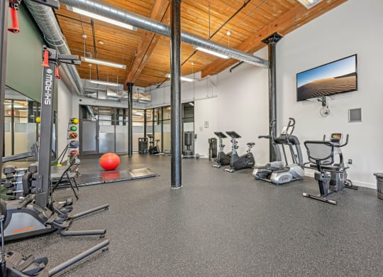 a gym with cardio equipment and weights on the floor and a tv at Riverwalk Apartments, Lawrence, MA