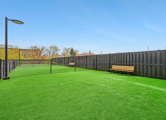 a yard with a tennis court and benches at Riverwalk Apartments, Lawrence, MA