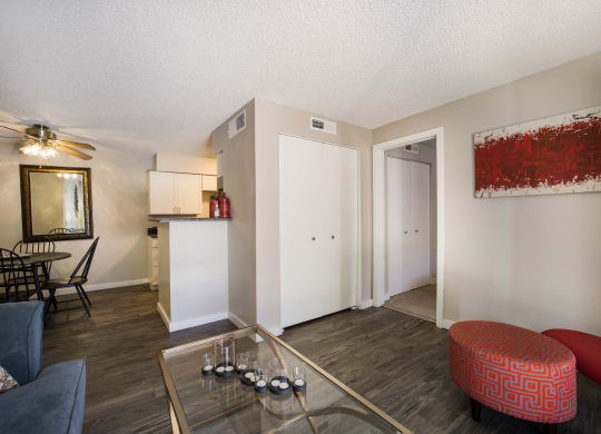 Living room with a glass coffee table and a red ottoman at Windmill Apartments, Colorado, 80916