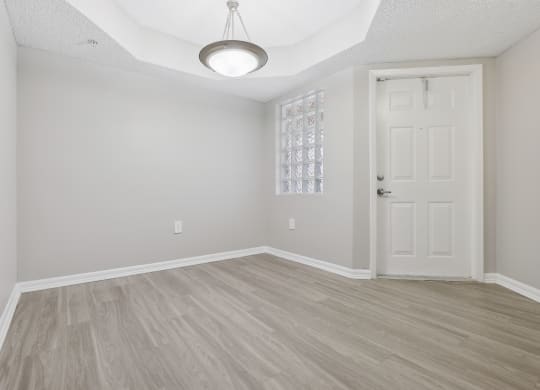 an empty living room with a white door and wood flooring at Pembroke Pines Landings, Pembroke Pines