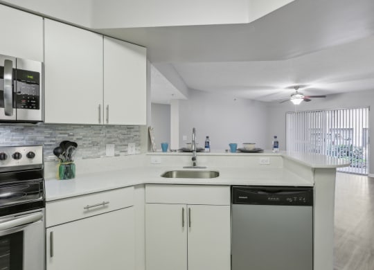 a kitchen with white cabinets and a sink and a stove at Pembroke Pines Landings, Florida