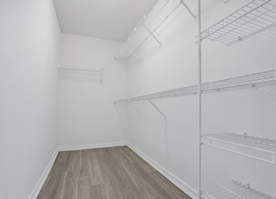 an empty room with white walls and wood flooring and a white closet with shelves at Pembroke Pines Landings, Pembroke Pines, Florida