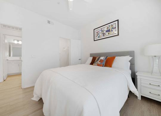 A bedroom with a large bed and a white dresser.