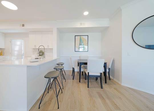 A kitchen with white cabinets and a white island with a bar stool.