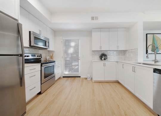 A kitchen with white cabinets and a wooden floor.