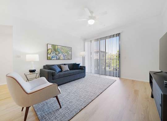A living room with a grey couch, a white chair, and a painting on the wall.