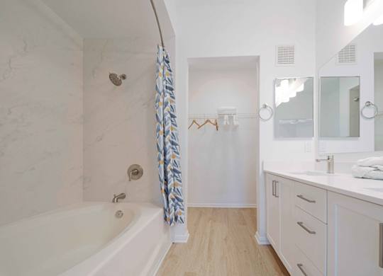 A white bathroom with a tub, sink, and mirror.